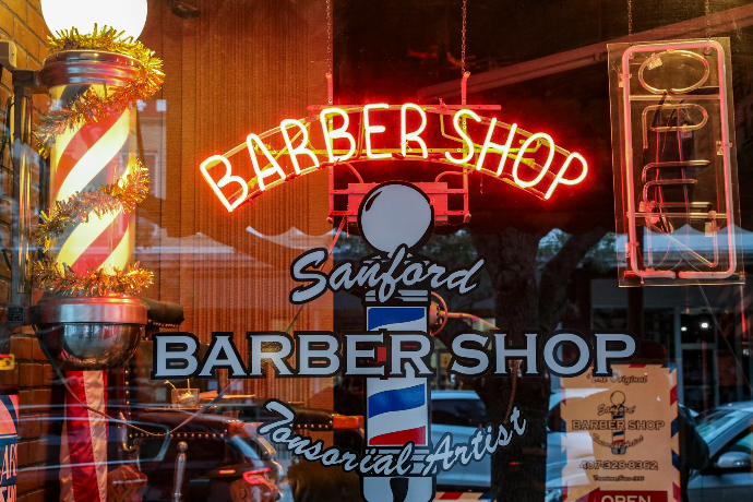 a barber shop with a neon sign in the window